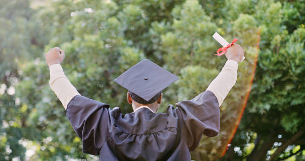 Graduate, success and education, celebrate graduation with certificate and pride for achievement. Winner, fist and academic event, degree with college diploma and happiness outdoors in cap and gown.